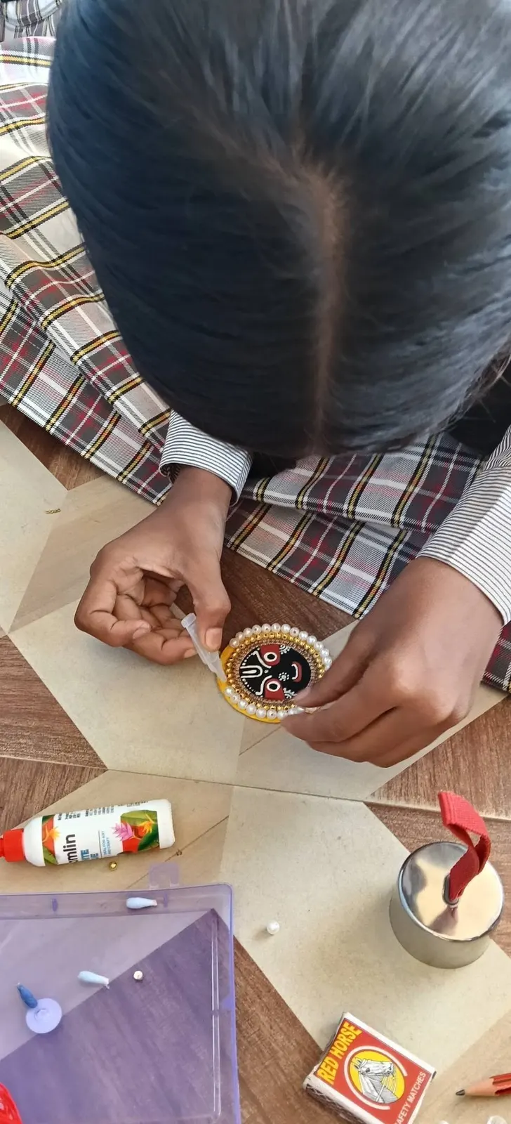 A student makes a rakhi by hand for the Rakhi Making Competition