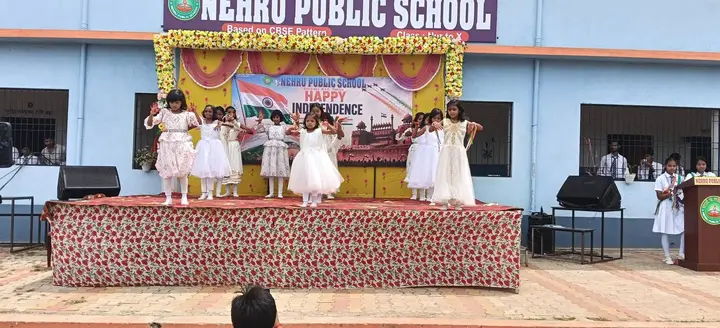 Junior students in white frocks dance on stage