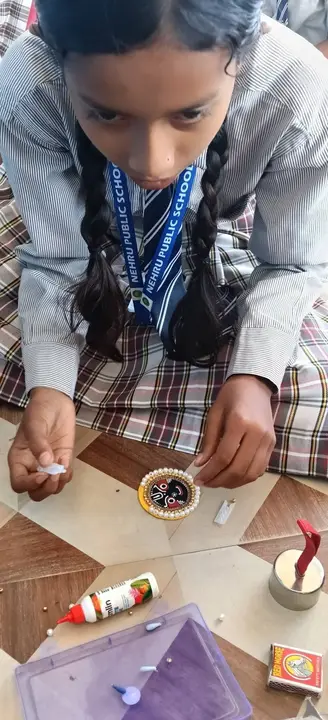 A student decorates a handmade rakhi